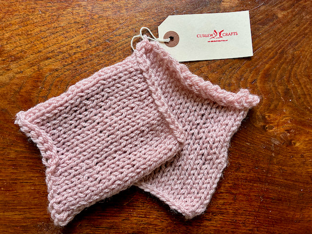 Single Pastel Pink Set of Knitted Cleaning Cloths on a wooden surface