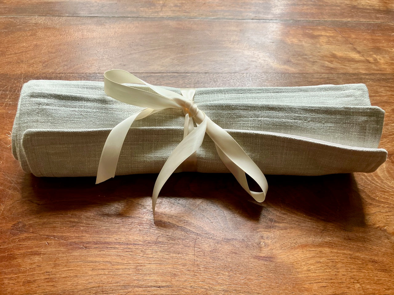 Set of 4 Natural Linen Place Mats rolled up with a Cream ribbon by Curlew Crafts