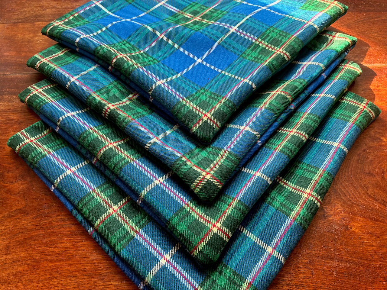 Four Green and Blue Tartan Cushion Covers n a wooden surface