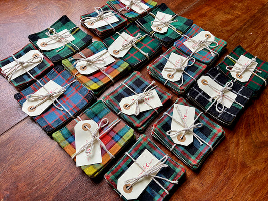 Assorted packaged sets of Tartan Coasters on a wooden table