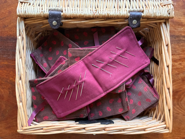 Wicker Basket of Chestnut and Rose Pink Needle Cases with one open with needles in