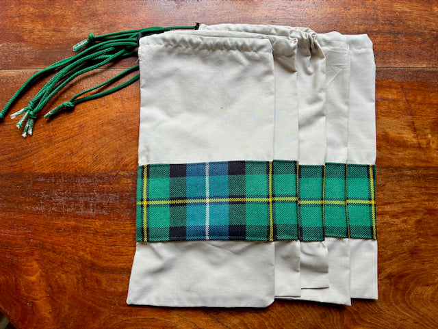 Five banded Tartan Drawstring Bags on a wooden table