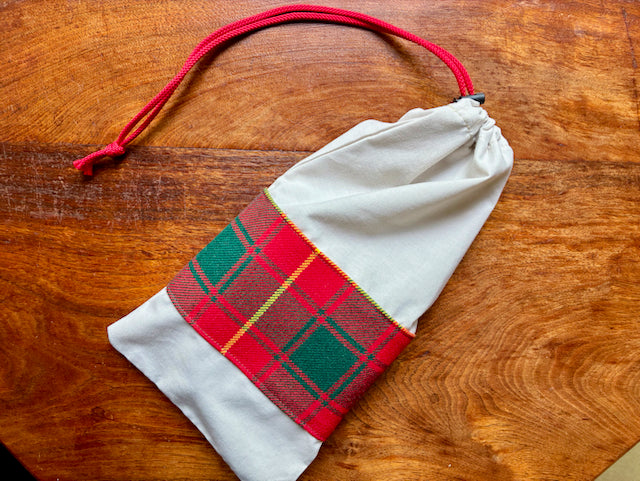 Full Red Tartan banded Drawstring bag on a wooden surface