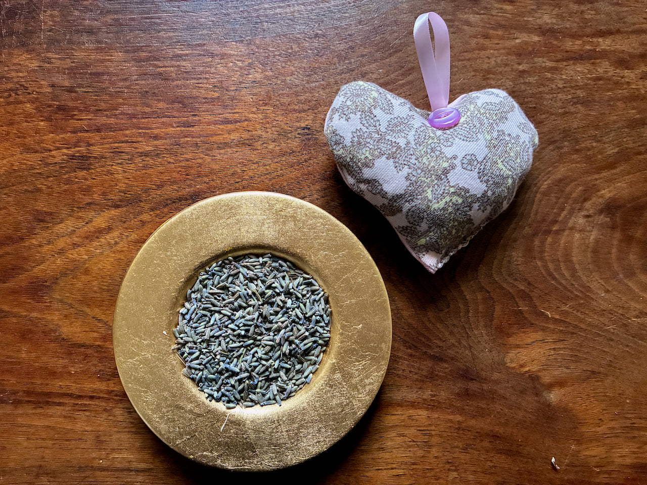 A Grey and Pink Paisley Lavender Sachet by a bowl of dried avender
