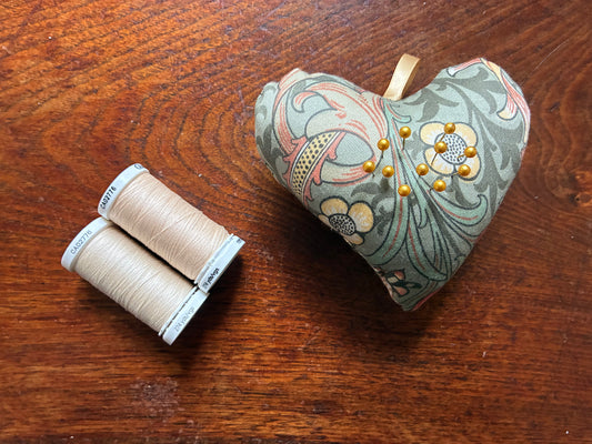 William Morris Heart Pincushion by Two reels of Thread on a wooden surface