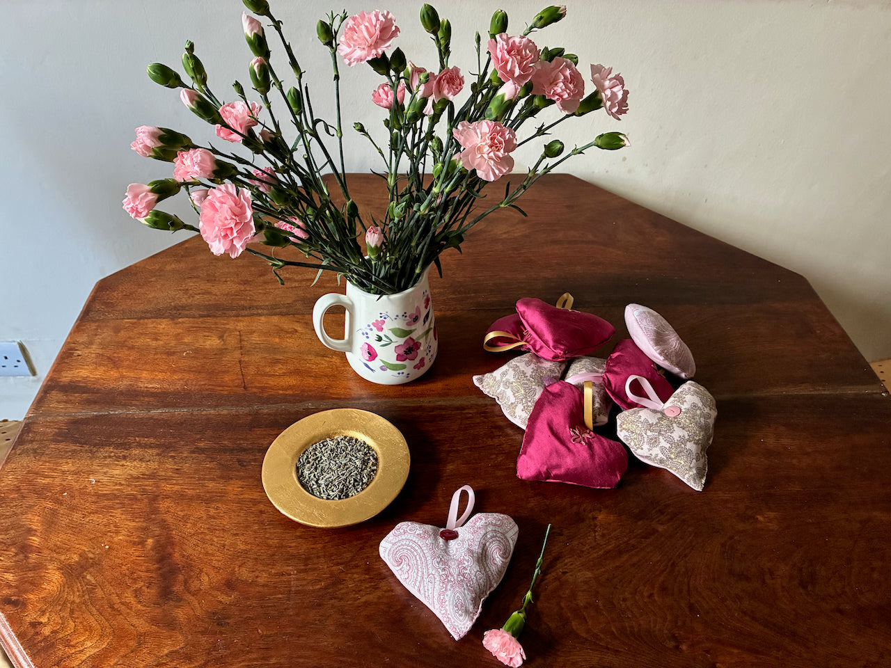 A heart shaped Red and White Paisley Lavender Sachet with flowers and a bowl of dried Lavender
