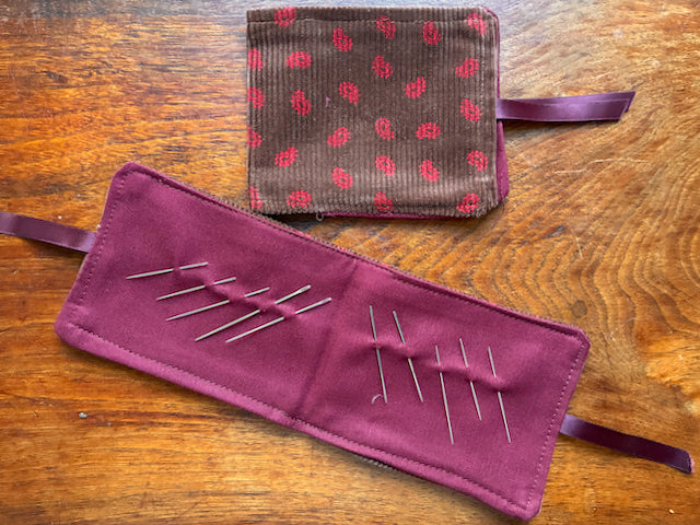 Two Chestnut and Rose Pink Needle cases, one open and one closed, with sewing needles in