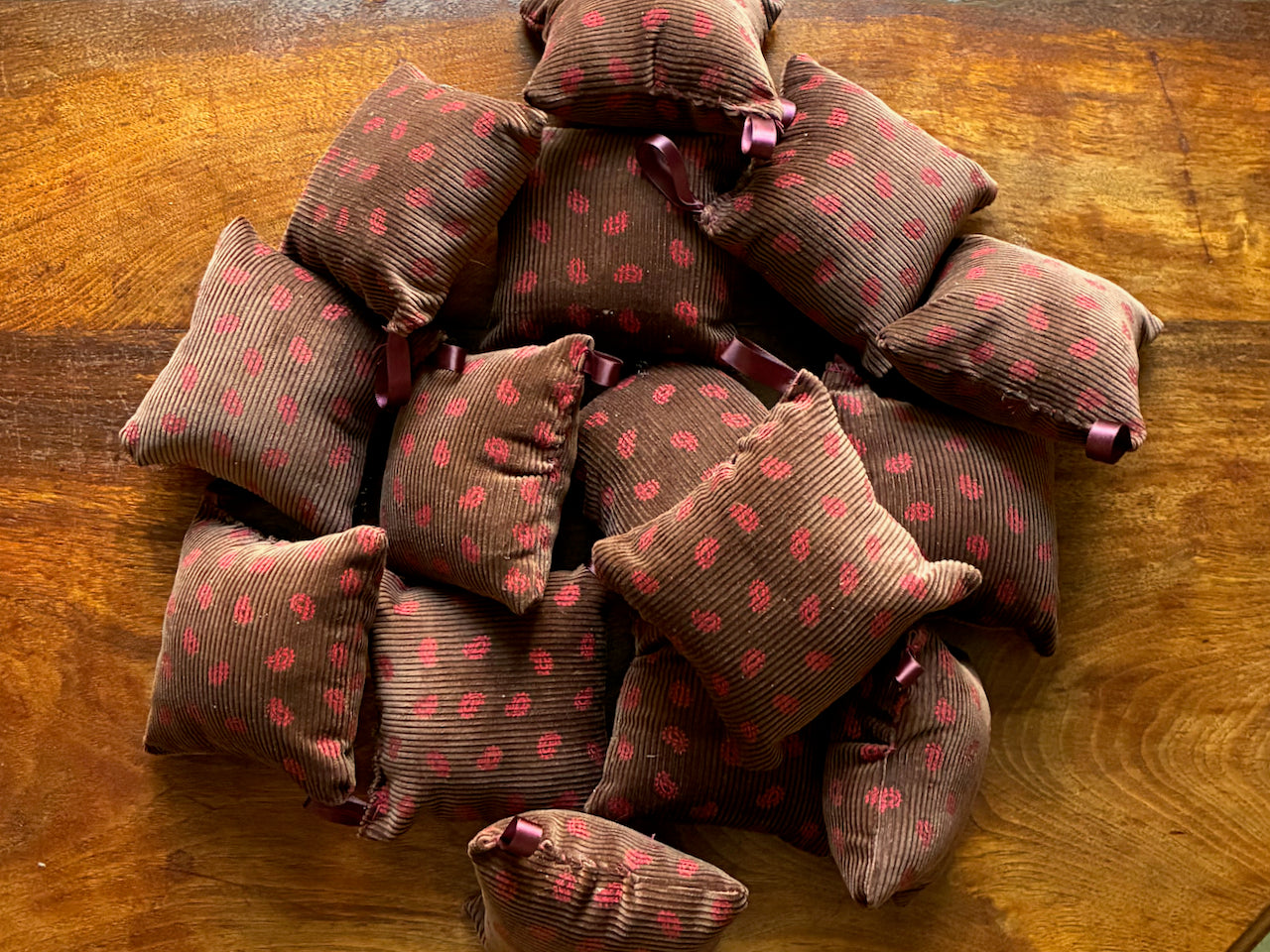 Chestnut and Rose Pink Paisley Pincushions on a wooden surface