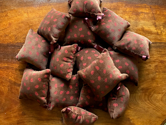 Pile of Chestnut and  Rose Pink Pincushions on a wooden surface