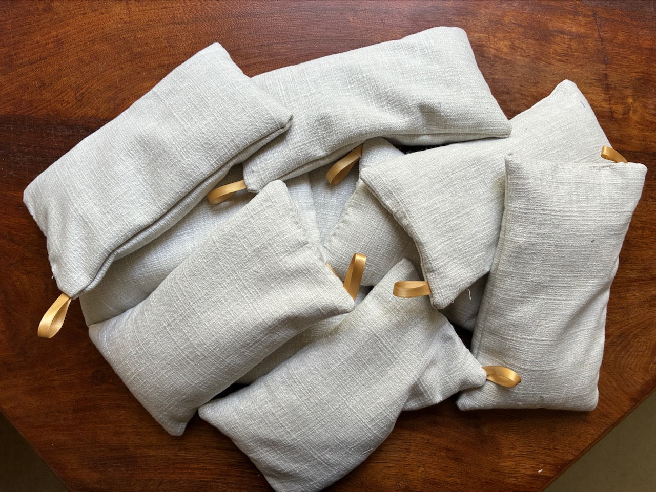 Pile of Small Linen Wheat Bags with ribbon hooks by Curlew Crafts