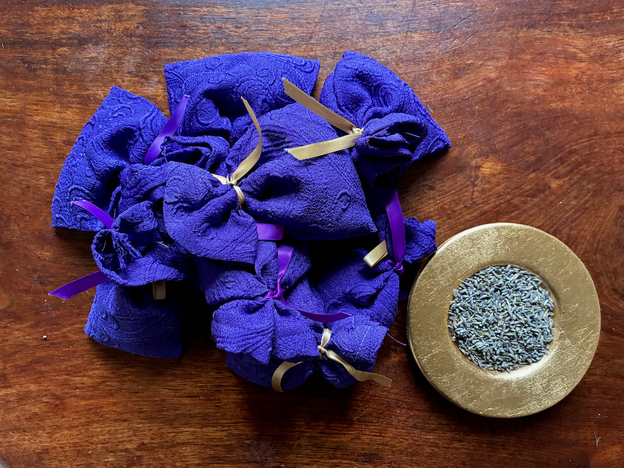 Purple Lavender Sachets and  Saucer of Dried Lavender on a wooden surface