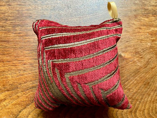 Red and gold Art Deco Chenille Pincushion on a wooden surface