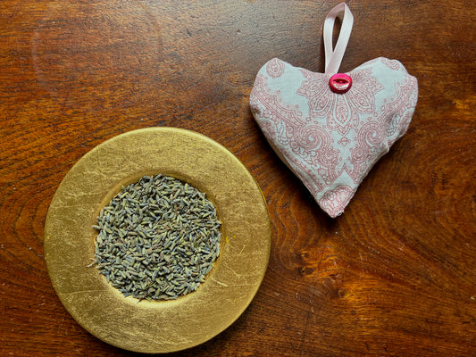 One Red and White Paisley Heart Lavender Sachet by a saucer of ried Lavender