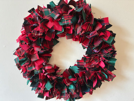 Seasonal circular Winter Wreath with Red, Green, and Gold Colours on a cream wall