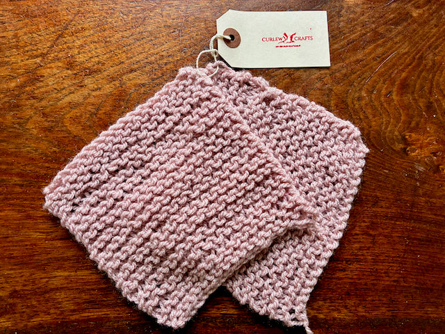 One Pastel Pink Set of Knitted Cleaning Cloths on a wooden surface 