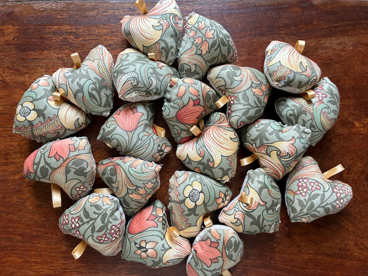 Collection of Small William Morris Heart Pincushions on a wooden surface