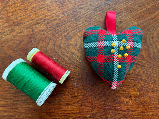 Small Tartan Heart Pincushion with two reels of Thread on a wooden surface