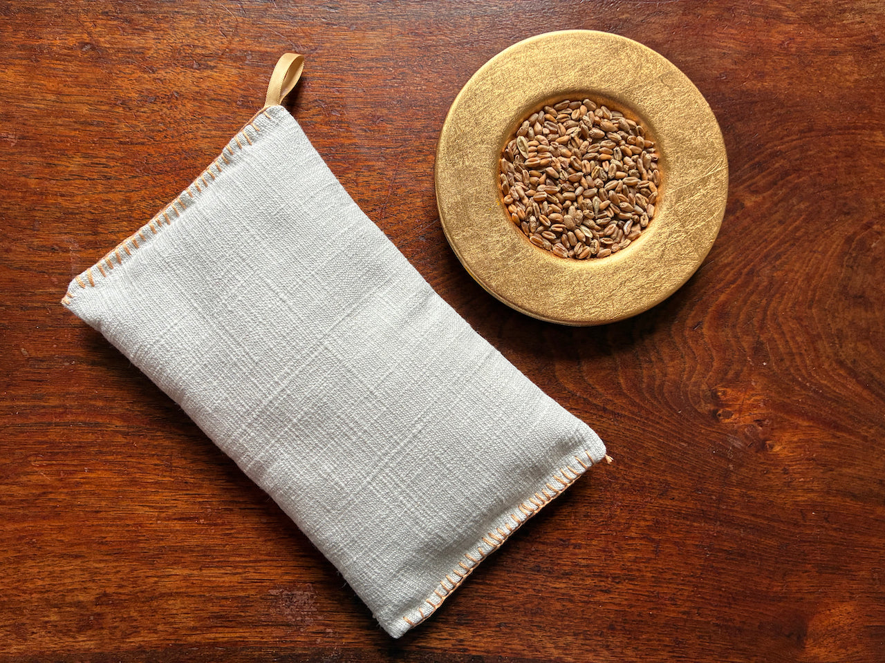 Small Linen Wheat Bags by a gold bowl of Wheatgrain on a wooden surface