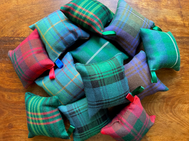 Assorted Tartan Pincushions with Satin ribbon hooks on a wooden surface