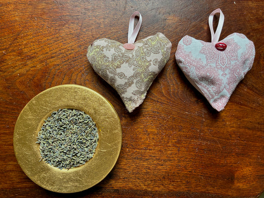 Two Matching Pink Paisley Heart Lavender Sachets by a saucer of Dried Lavender