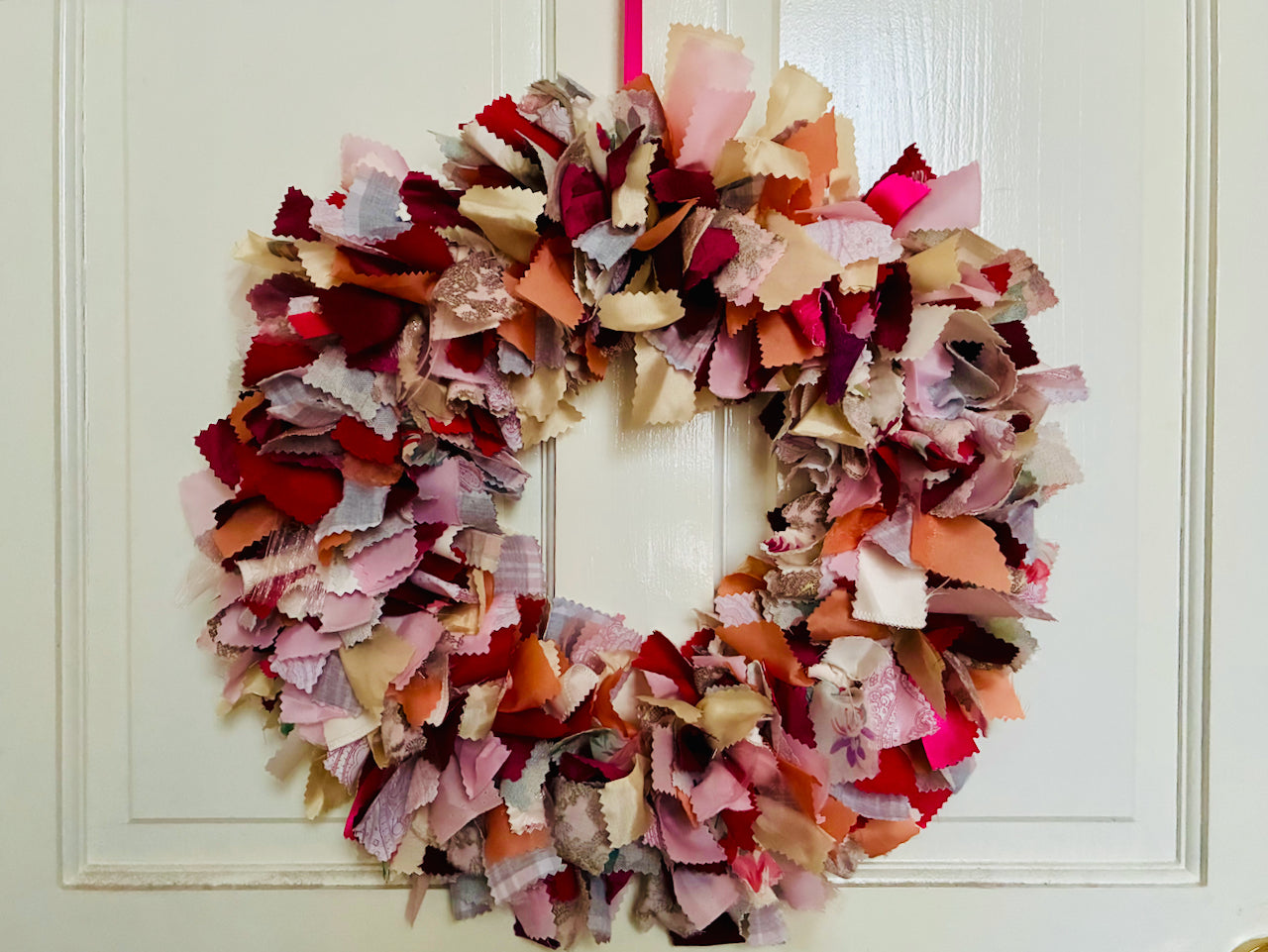 Colourful circular Valentine wreath hanging on a white paneled door