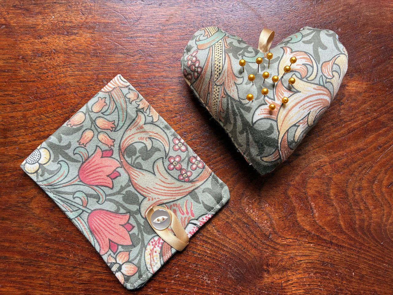 William Morris Needle Case and Heart Pincushion Sewing Set with Pins on a wooden surface