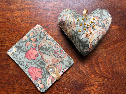William Morris Needle Case and Heart Pincushion Sewing Set with Pins on a wooden surface