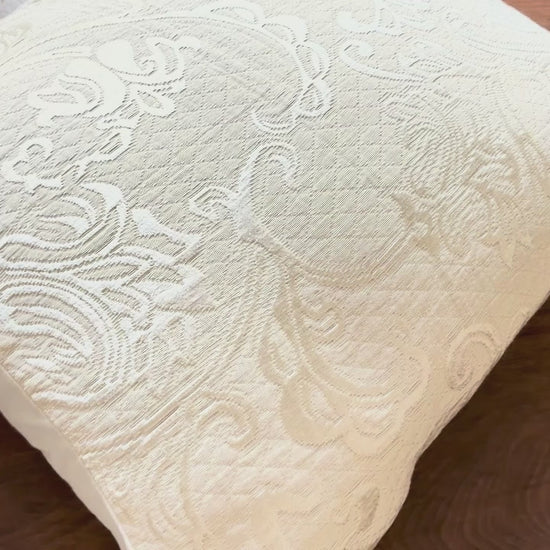 Cream Brocade filled Cushion Cover on a wooden table
