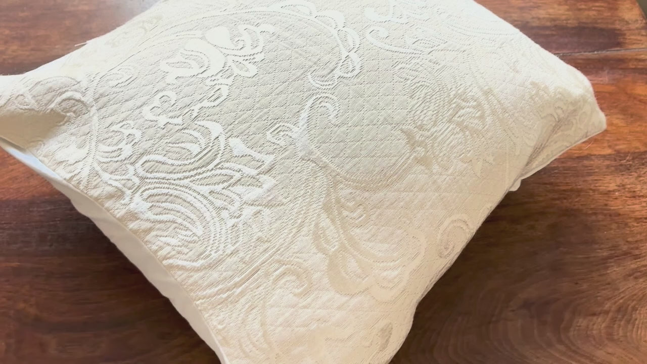 Cream Brocade filled Cushion Cover on a wooden table