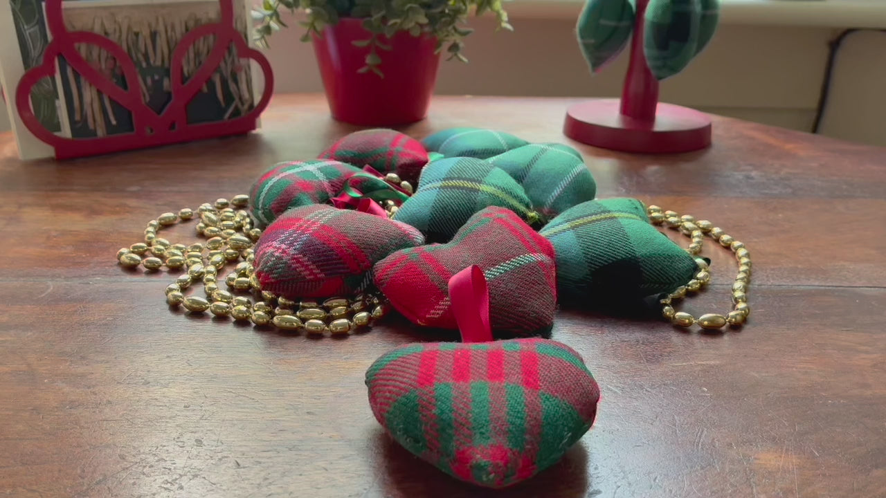 Assorted small decorative Tartan Hearts with a string of Gold beads on a wooden surface