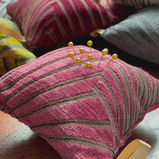 Pink Art Deco Pincushion with Gold Pins on a wooden surface