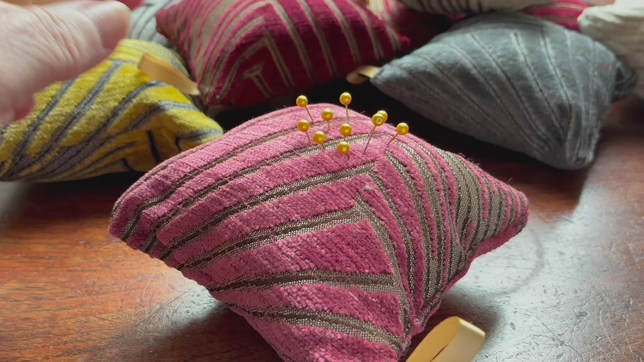 Pink Art Deco Pincushion with Gold Pins on a wooden surface