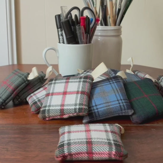 Square Tartan Clove Sachets on a wooden surface with containers of pens and paintbrushes