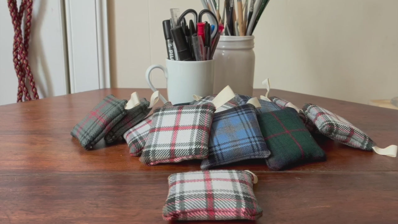 Square Tartan Clove Sachets on a wooden surface with containers of pens and paintbrushes