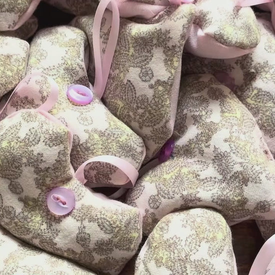 Pile of Grey and Pink Heart shaped Lavender Sachets on a wooden surface