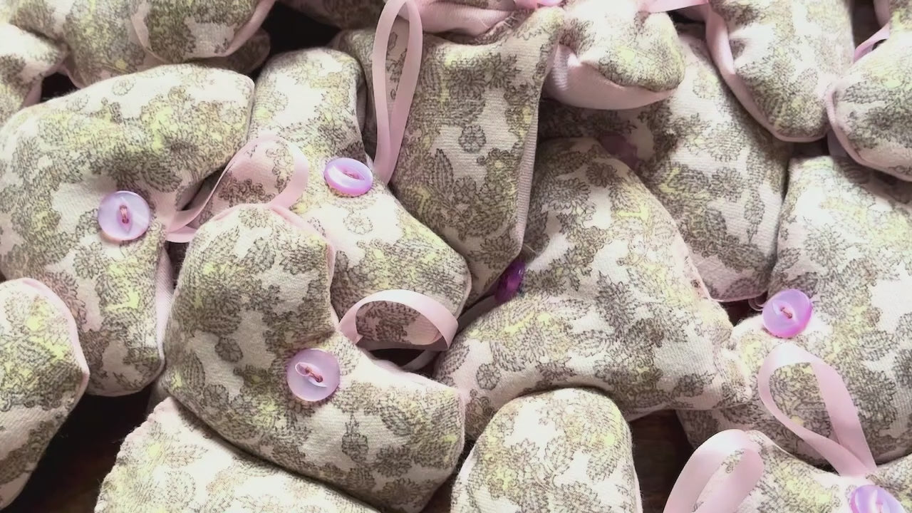 Pile of Grey and Pink Heart shaped Lavender Sachets on a wooden surface