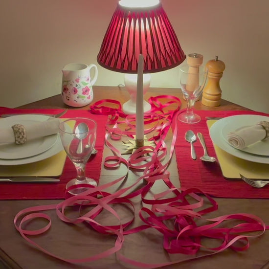 Circular Wreath in romantic reds pinks and golds by a dining table set for two people