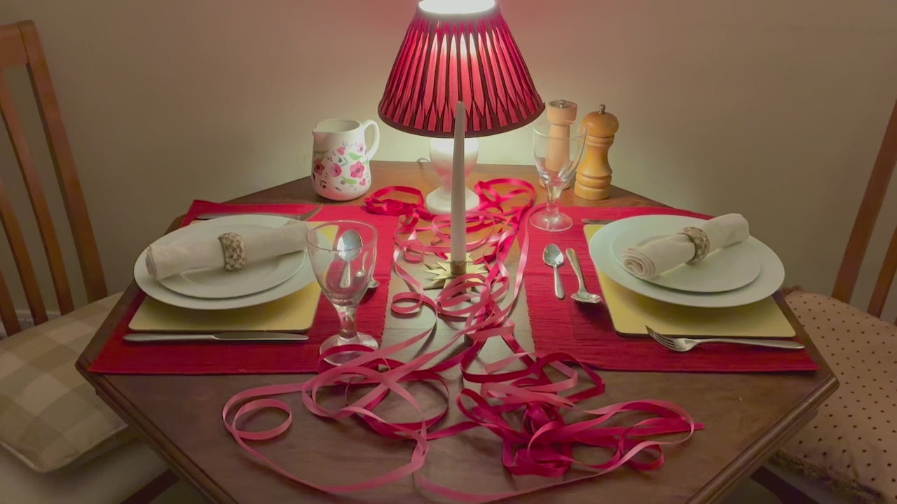 Circular Wreath in romantic reds pinks and golds by a dining table set for two people