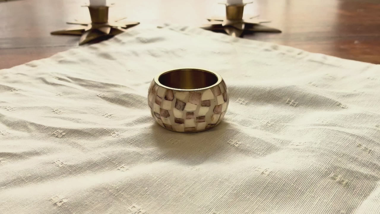 Cream Brocade Napkin being put into a Napkin ring on a wooden table