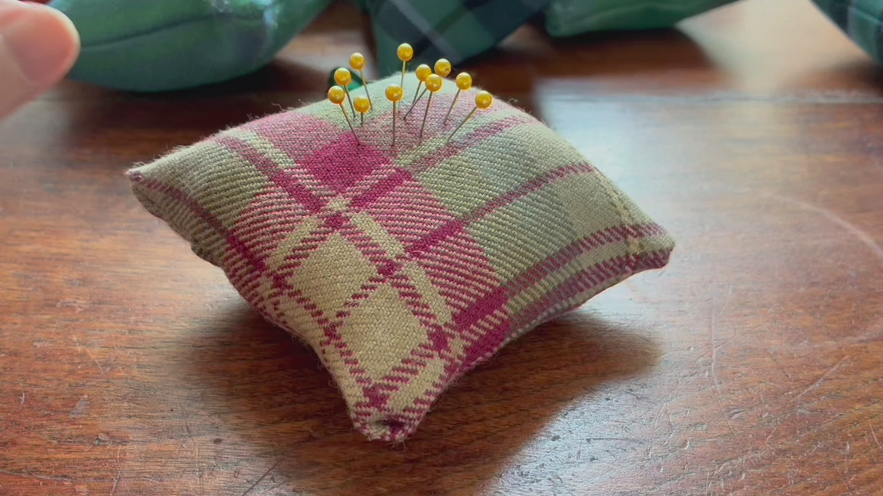Square Tartan Pincushion with a Satin ribbon and pins in on a wooden surface