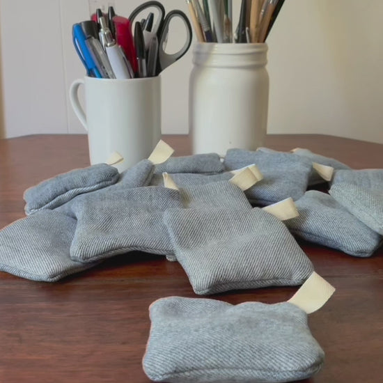 Collection of Denim Clove Sachets on a wooden surface with jars of pens and paint brushes