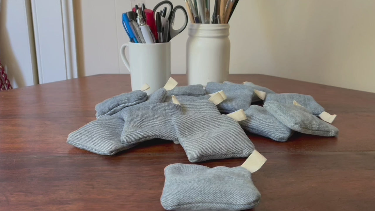 Collection of Denim Clove Sachets on a wooden surface with jars of pens and paint brushes