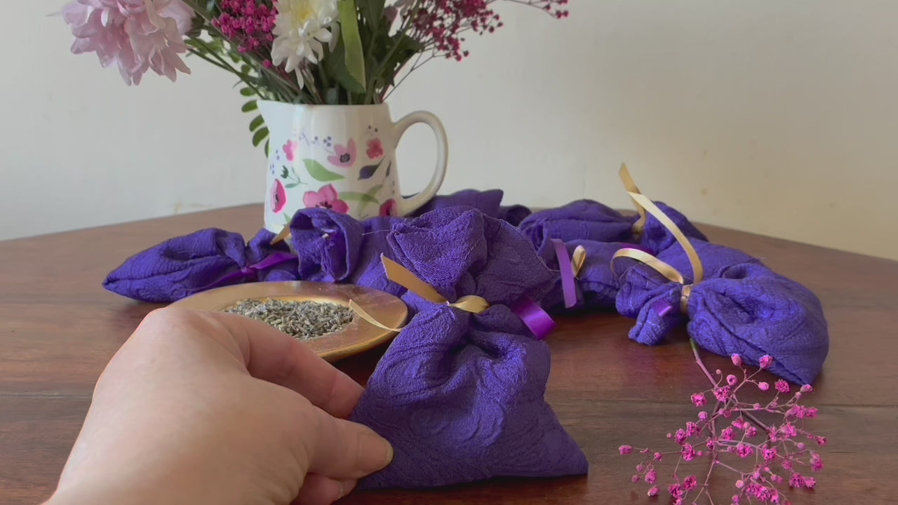 One Purple Lavender Sachet with a saucer of Dried Lavender and a vase of Pink flowers